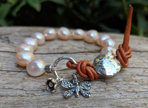 This beautiful one-of-a-kind chic handmade artisan bracelet combines beautiful soft pink-peach baroque pearls with sterling silver flower and butterfly charms, accented by leather elements for an organic look. The beautiful natural rose pink shades radiate chic femininity, staying true to nature. 