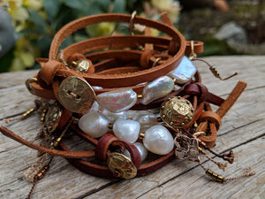 Handmade boho natural baroque pearl leather wrap bracelet with gold bronze button and heart charm. The artisan bracelet is adjustable as leather knots can be moved for a perfect fit. The gold bronze heart charm can freely move along the leather cord. A modern take on boho chic style jewelry showcasing natural pearls and leather.