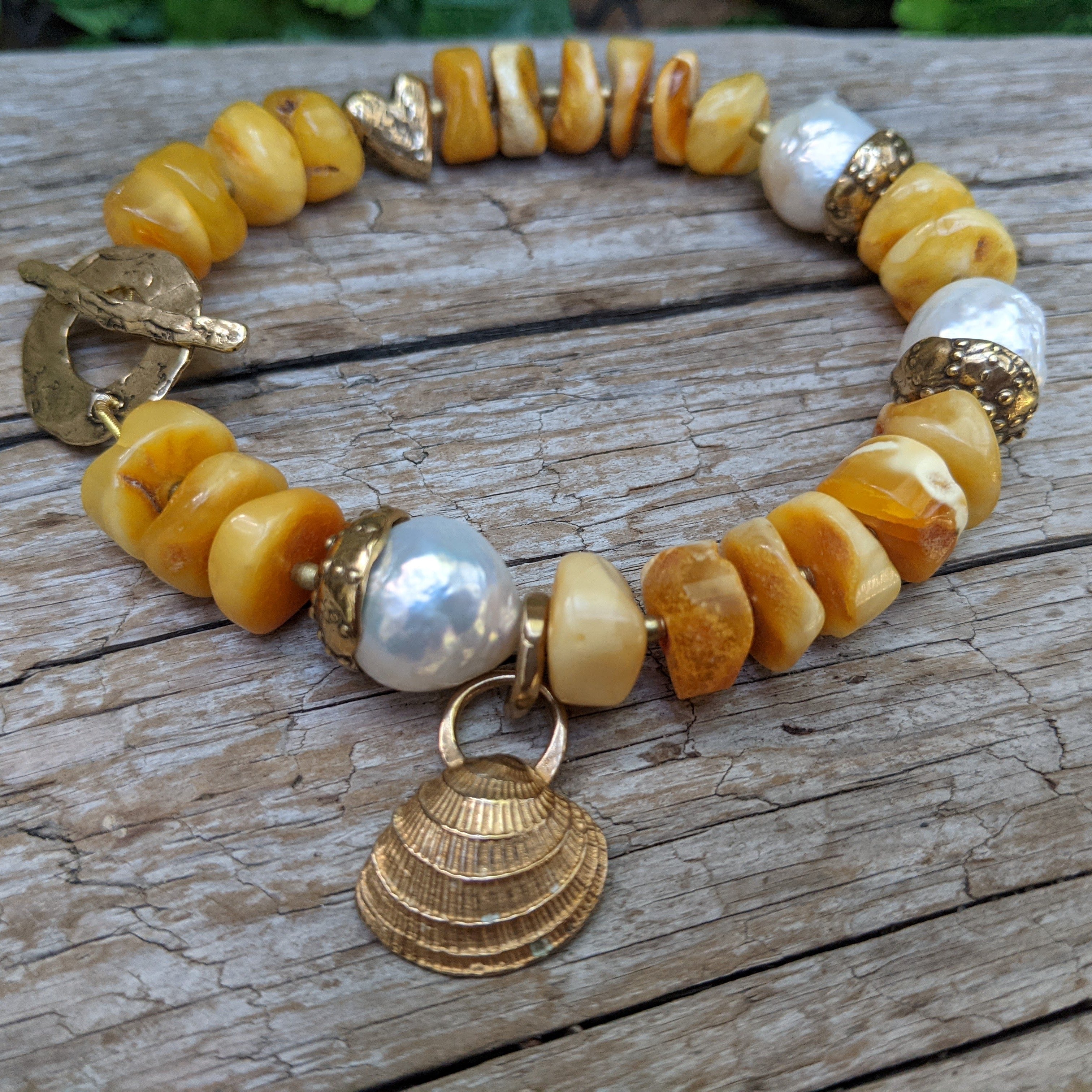 Statement Baltic amber bracelet with big white Edison pearl and artisan gold bronze shell handcrafted by Aurora Creative Jewellery.