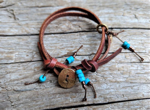Handmade boho natural turquoise leather wrap bracelet with gold bronze button and heart charm. The artisan bracelet is adjustable as leather knots can be moved for a perfect fit. The gold bronze heart charm can freely move along the leather cord. A modern take on boho chic style jewelry showcasing natural turquoise and leather.