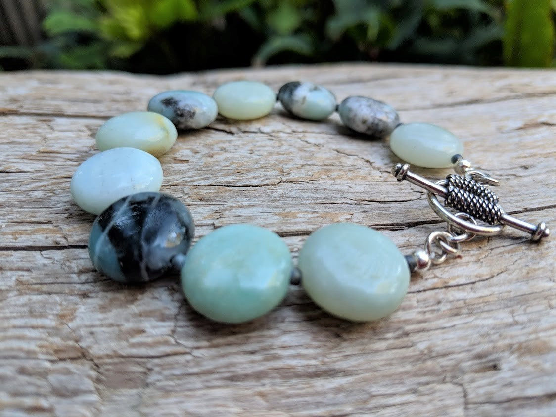 This beautiful handmade artisan toggle bracelet showcases the beauty of natural amazonite gemstone. The calm blues, mints, grays, and natural beiges of amazonite feel refreshing complimented by sterling silver elements. The bracelet was designed with simplicity in mind, to keep the focus on the natural textures of the beautiful stone.