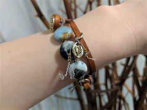 This fun handmade artisan boho leather wrap bracelet showcases the beauty of natural textures. The calm blues, grays, and natural beiges of amazonite gemstone feel refreshing  on the background of natural leather.  The bracelet is finished off with a gold bronze button and leather loop. A heart charm adds another touch of gold and an element of fun. The heart charm can freely move around the bracelet so you can enjoy it from all sides. 