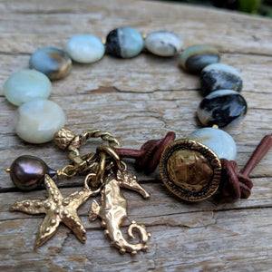 Light blue and gray amazonite stone bracelet with gold bronze seahorse and starfish charms, black pearl, and button, by Aurora Creative Jewellery