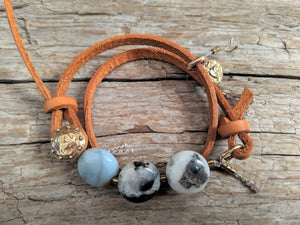 This fun handmade artisan boho leather wrap bracelet showcases the beauty of natural textures. The calm blues, grays, and natural beiges of amazonite gemstone feel refreshing  on the background of natural leather.  The bracelet is finished off with a gold bronze button and leather loop. A heart charm adds another touch of gold and an element of fun. The heart charm can freely move around the bracelet so you can enjoy it from all sides. 