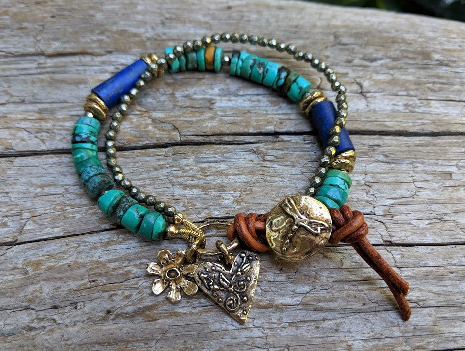 Gorgeous vibrant handmade one-of-a-kind artisan bracelet showcasing the beauty of natural textures. The intoxicating large green Tibetan turquoise beads are complemented beautifully by the deep blue lapiz lazuli, pyrite and brown leather color and texture. Gold bronze elements including the gold bronze flower and floral heart charms and dragonfly button add some shine to the combination.