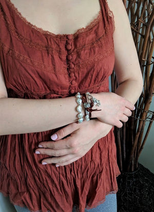 This gorgeous handmade artisan wrap bracelet-necklace combines the beautiful large white baroque pearls with sterling and leather elements. The sterling silver button, seahorse and star charms add a beautiful shine to the combination and create an ocean theme. The bracelet is held together by a silk thread and a brown leather cord. Wearing this bracelet feels like taking a refreshing walk on the beach. 