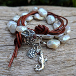 This gorgeous handmade artisan wrap bracelet-necklace combines the beautiful large white baroque pearls with sterling and leather elements. The sterling silver button, seahorse and star charms add a beautiful shine to the combination and create an ocean theme. The bracelet is held together by a silk thread and a brown leather cord. Wearing this bracelet feels like taking a refreshing walk on the beach. By Aurora Creative Jewellery