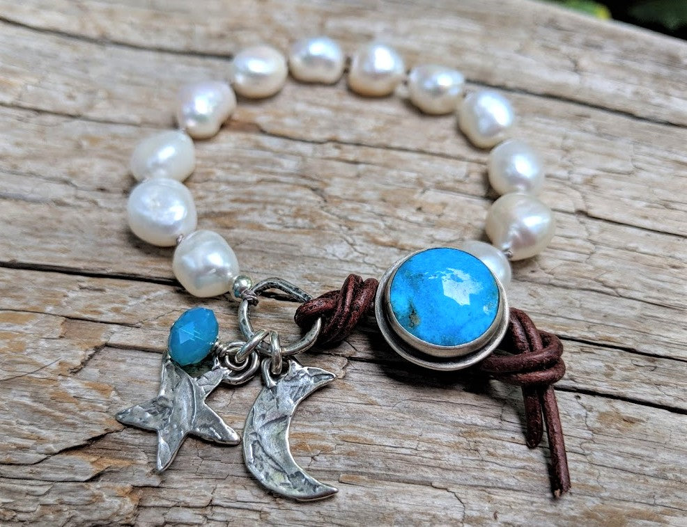 This gorgeous handmade artisan bohemian chic statement bracelet showcases the large white baroque fresh water pearls and contrasting bright turquoise button and artisan sterling silver crescent moon and star charms. The charms create a beautiful night theme and the white pearls resonate with the shine of white moon. A beautiful fresh touch of white pearls on your wrist contrasted by a blue accent is a perfect accessory. The handmade button on this bracelet is unique as it has sterling silver setting. 