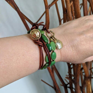 This handmade artisan bracelet combines the gorgeous forest greens of chrysoprase with natural leather, pearl, and gold bronze elements. The brown leather adds a contrasting texture to the combination, while complementing the colors of the stone. The Spanish cross Reale coin charm creates a rustic-medieval theme. A white pearl accent adds a fresh contrast to the combination of natural greens. 