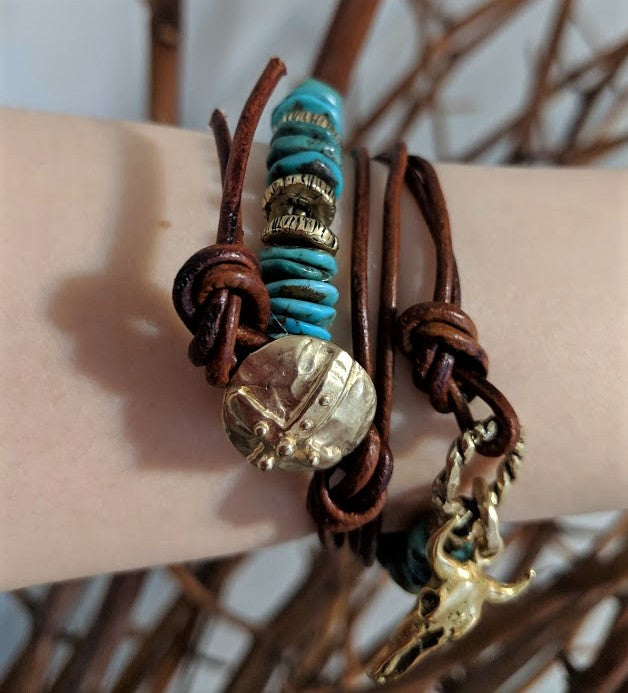 This fun handmade artisan one-of-a-kind wrap bracelet showcases the natural bright Tibetan turquoise, complimented by leather and gold bronze elements. In a modern take on gemstone jewelry we combine charms with leather accents to complement the texture of the stone. The large gold bronze cow skull charm adds a unique touch and creates a western cowgirl theme. 