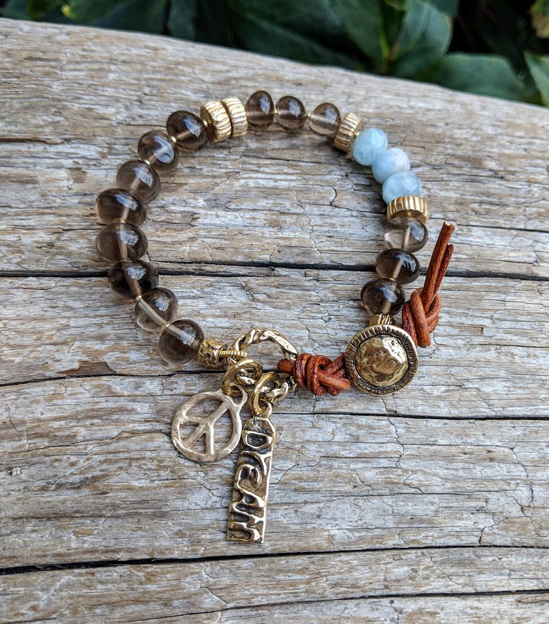 A gorgeous handmade artisan bracelet showcasing the beauty of natural gray-brown smoky quartz combined with sky blue aquamarine. The gemstones are beautifully complimented by gold bronze elements creating a dream and peace theme.