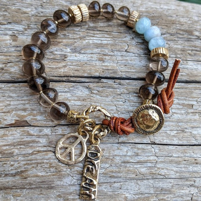 Smoky quartz and aquamarine bracelet with gold bronze peace and dream charms and button, by Aurora Creative Jewellery