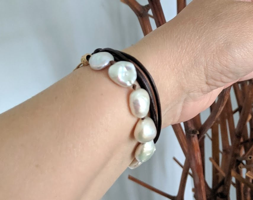 This handmade artisan wrap bracelet combines the gorgeous large white baroque pearls with gold bronze and leather elements. The bracelet is held together by a silk thread and a dark brown-black leather cord. The cross linker and button detail add a medieval or rustic look to the combination.  A beautiful accessory to add both femininity and texture to your outfit.