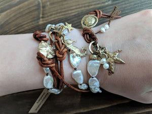 This gorgeous handmade artisan wrap bracelet-necklace combines the beautiful large white baroque pearls with gold bronze and leather elements. The gold bronze button, seahorse and star charms add a beautiful shine to the combination and create an ocean theme. The bracelet is held together by a silk thread and a brown leather cord. Wearing this bracelet feels like taking a night walk on the beach with the sky full of stars. 
