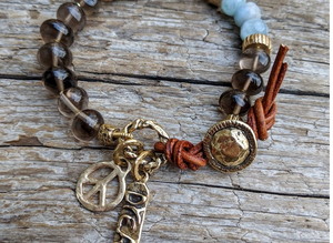 A gorgeous handmade artisan bracelet showcasing the beauty of natural gray-brown smoky quartz combined with sky blue aquamarine. The gemstones are beautifully complimented by gold bronze elements creating a dream and peace theme.