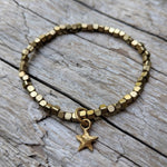 Tiny star delicate African brass bracelet with gold bronze star charm. Wear this bracelet alone or in a stack! It is elastic and very easy to put on and take off. By Aurora Creative Jewellery.