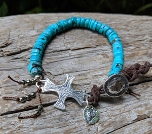 A vibrant modern handmade artisan one-of-a-kind bracelet showcasing the beauty of natural textures. The intoxicating blue turquoise is complemented beautifully by the leather color and texture. Sterling silver cross adds some shine to the combination and creates a religious theme. Tiny pyrite beads add more texture and natural sparkle.