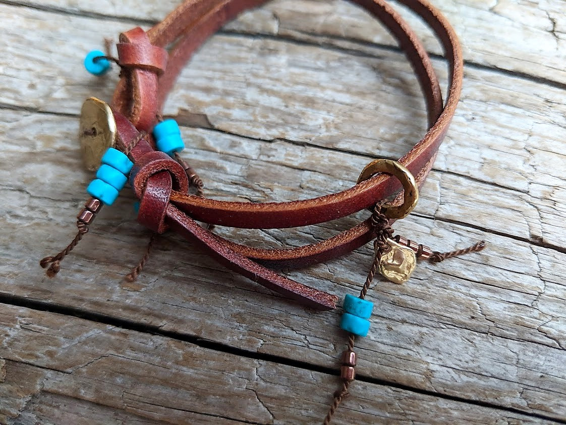 Handmade boho natural turquoise leather wrap bracelet with gold bronze button and heart charm. The artisan bracelet is adjustable as leather knots can be moved for a perfect fit. The gold bronze heart charm can freely move along the leather cord. A modern take on boho chic style jewelry showcasing natural turquoise and leather.